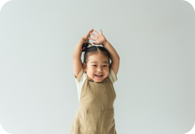 Little girl celebrating by throwing her hands in the air and smiling.